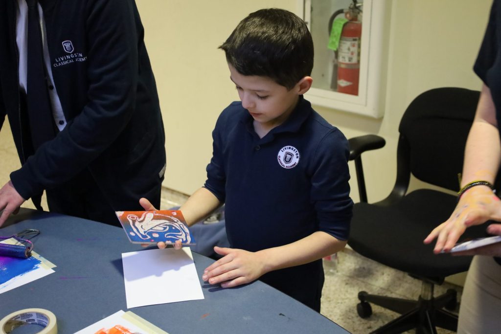 Young boy engaged in vibrant printmaking activity in a creative classroom environment.