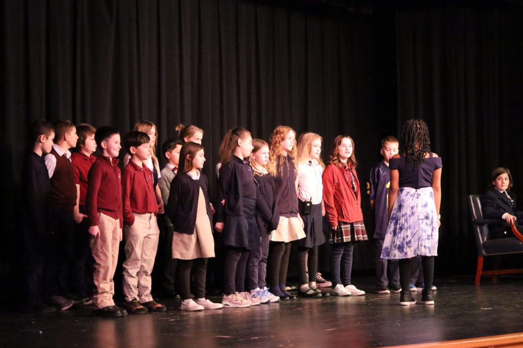 Children performing on stage in colorful outfits during a school talent show.