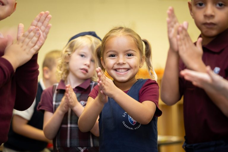 Children in a lively classroom joyfully clapping, showcasing youthful energy and engagement.