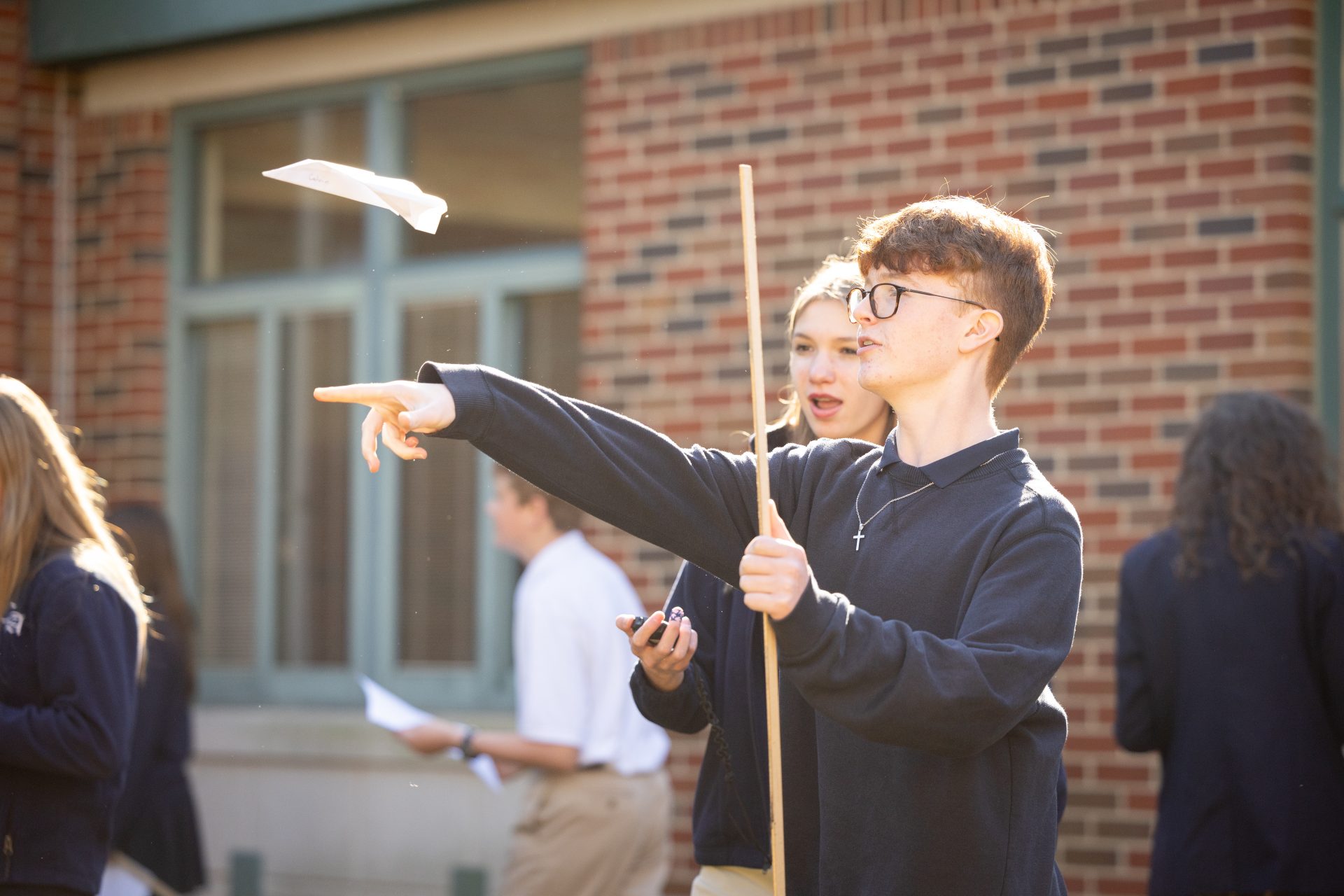 Young students launch paper airplanes outdoors, showcasing creativity and joyful camaraderie at school.